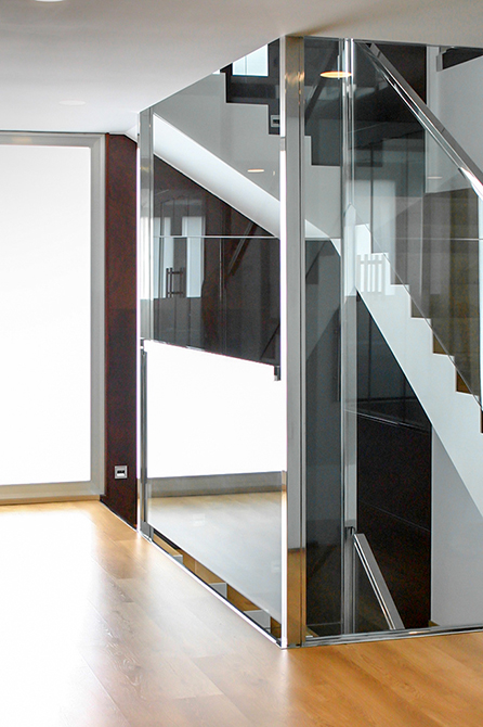 Escalera moderna con barandilla de acero y cristal con ventanal y mucha luz