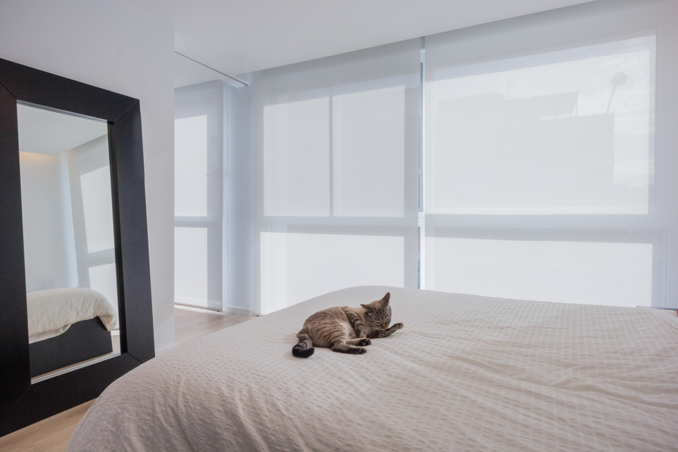 Dormitorio moderno en blanco con cama y gato en vivienda estilo nórdico - Chiralt Arquitectos Valencia