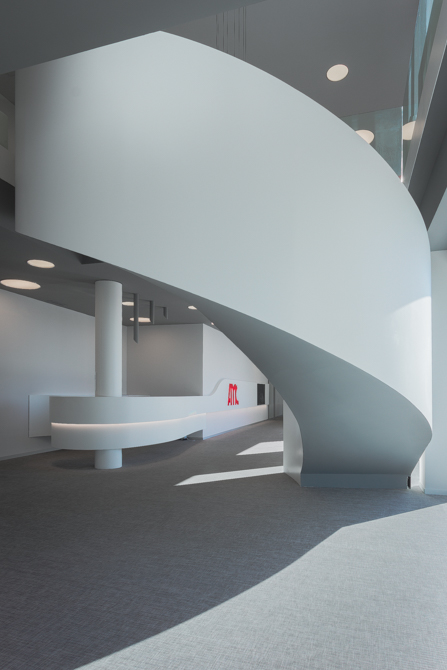 Escalera blanca en espiral en hall de oficinas modernas con mostrador en blanco y curva con iluminacion led