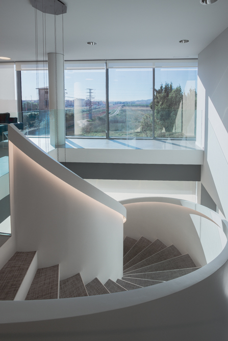 Escalera blanca en espiral en hall de oficinas modernas.
