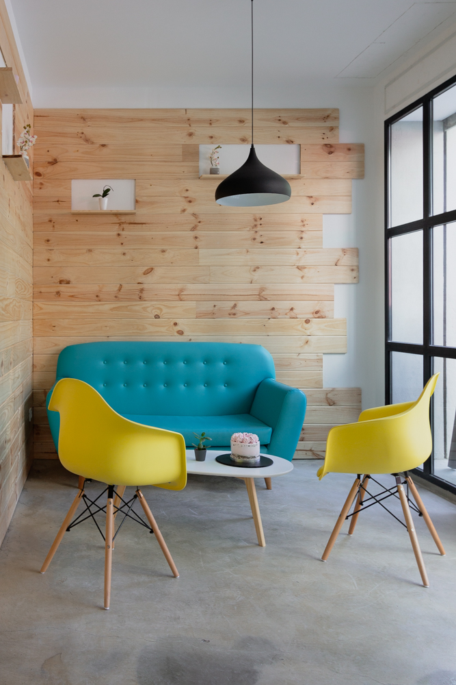 cafetería-de-diseño-en-Valencia moderna y colorida con parede de madera y suelo de hormigon con sofas de colores